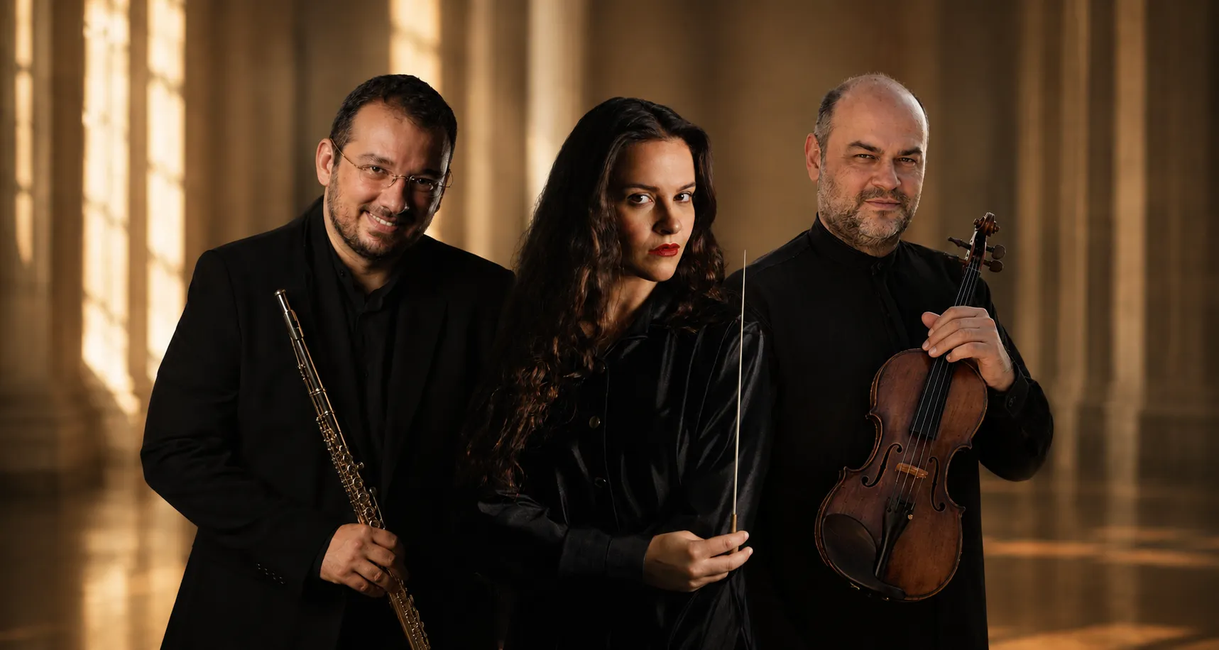 Conductor Maria Bazou stands between flutist Nikos Nikopoulos and violinist Apollon Grammatikopoulos in a warm editorial portrait for the Athens State Orchestra's performance of Music from Carmen, photographed in a luminous classical interior.
