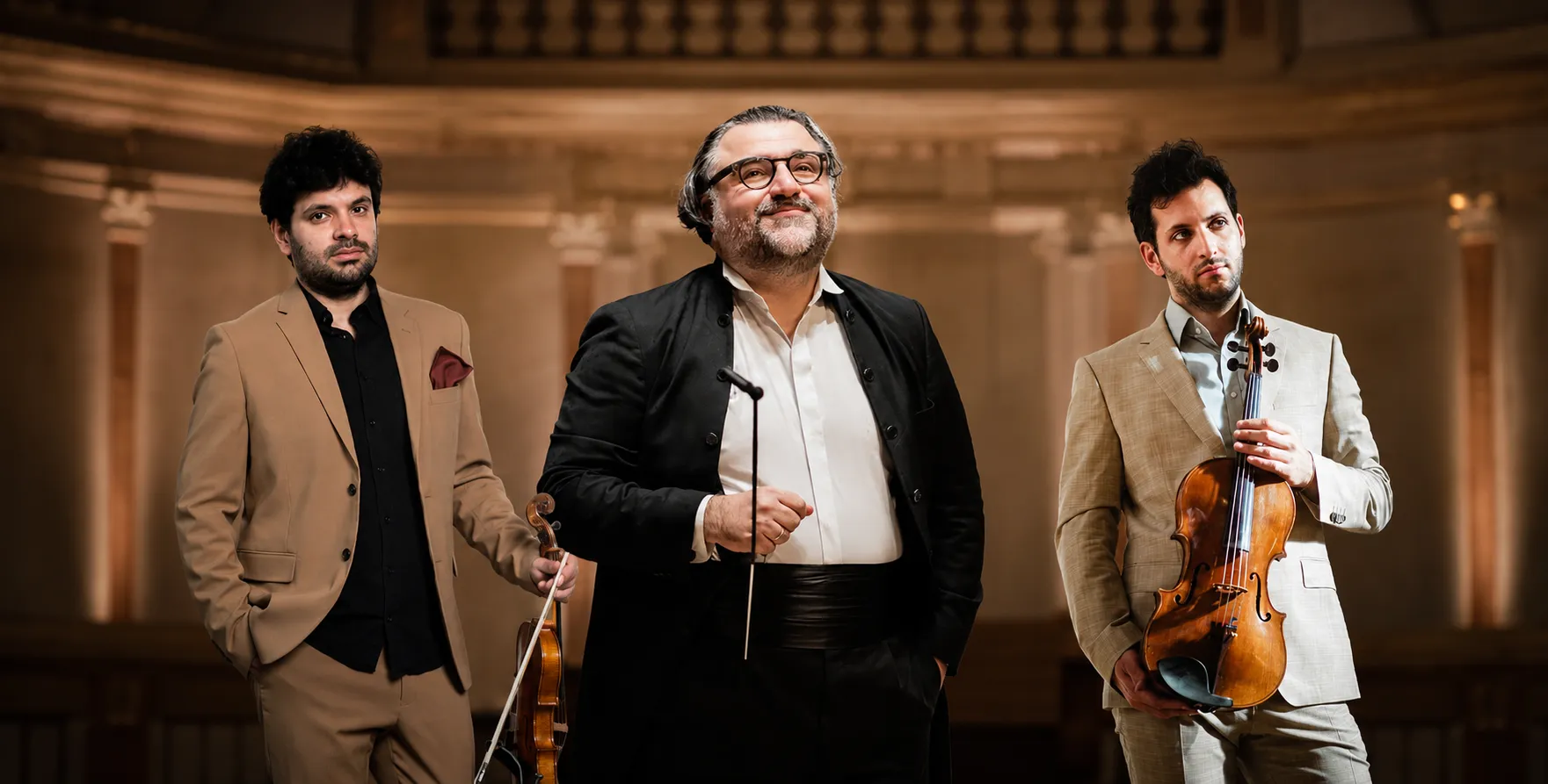 Conductor Georgios Balatsinos and cellist Pablo Ferrández in a cinematic concert hall portrait, standing in the middle of Iason Keramidis and Ilias-Ion Livieratos, elegant orchestral backdrop.